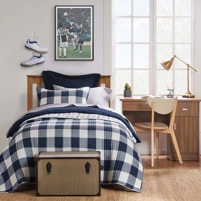Bedroom with plaid bedding, desk, and sports-themed decor