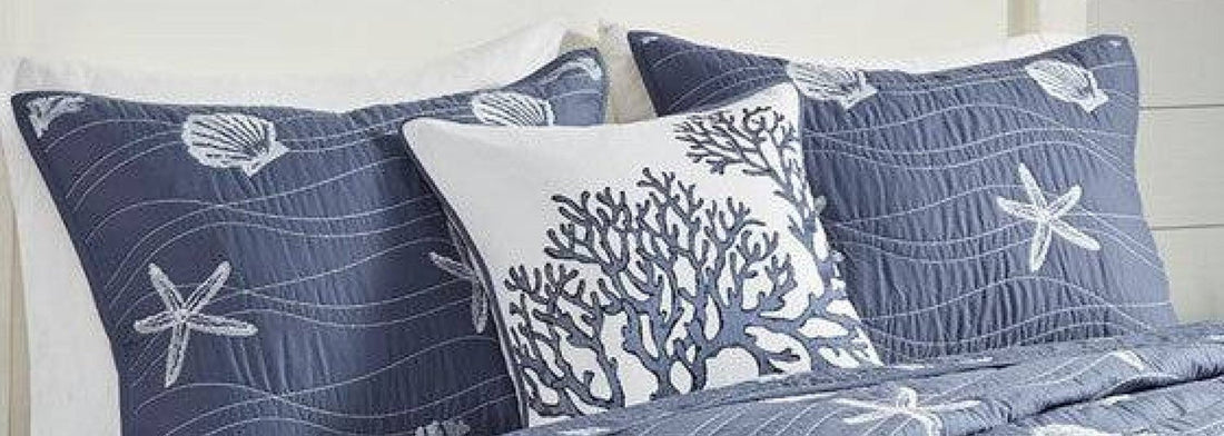 Layered coastal bedroom with soft blue bedding, natural textures, and relaxed seaside styling