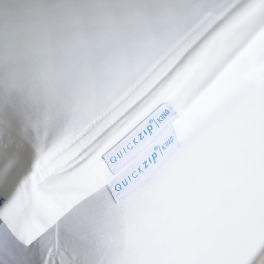 Close-up of a white bedding item, a  Quickzip Fitted Sheet , with two white labels reading QuickZip King.