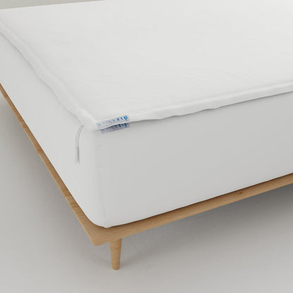 A close-up of a  Quickzip Fitted Sheet  resting on a light wood bed frame against a neutral gray background.