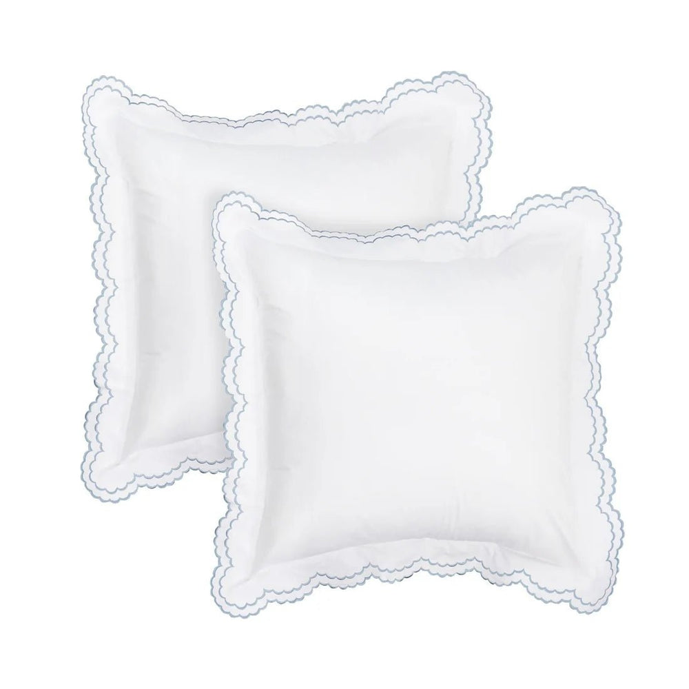 Two white square decorative pillows with scalloped edges, arranged overlapping on a plain white background.